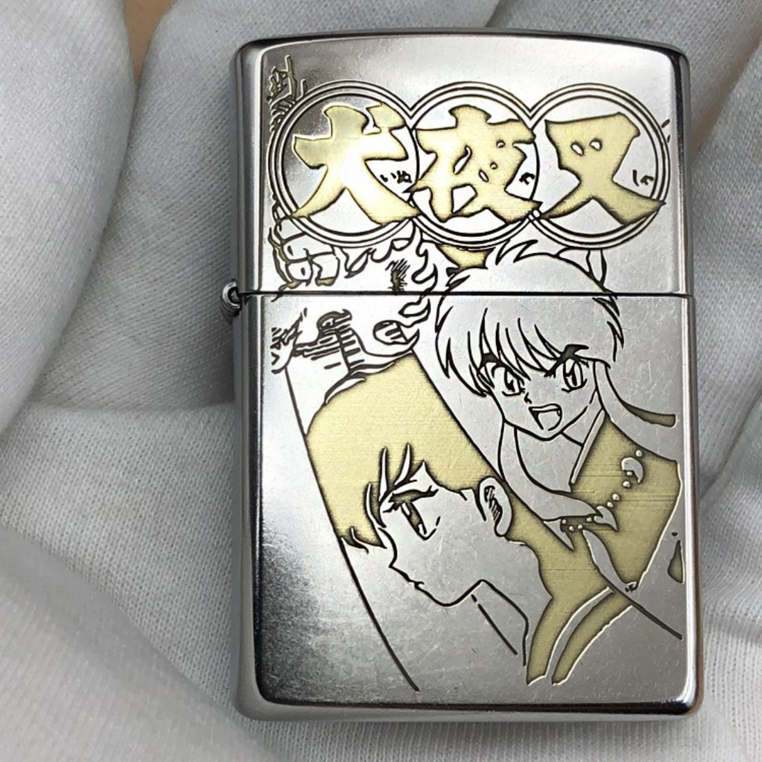 Front view of a Zippo lighter engraved with characters from the anime Inuyasha, featuring detailed golden accents.